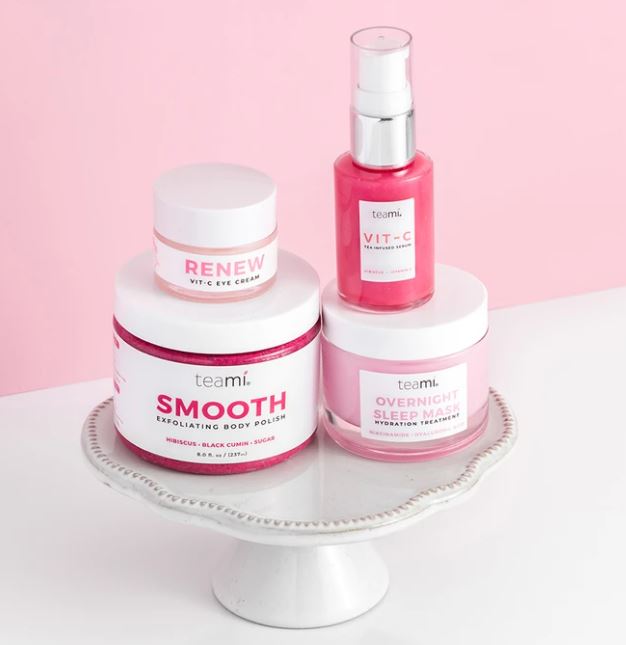 Teami Think Pink bundle products - overnight sleep mask, renew vit c cream, smooth body polish and vit c serum on marble stand and pink background