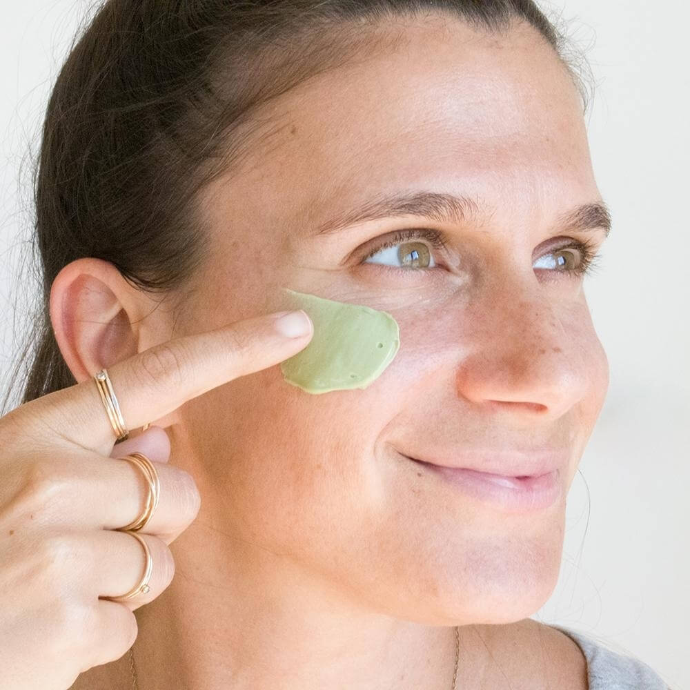 Woman applying Teami product to her face