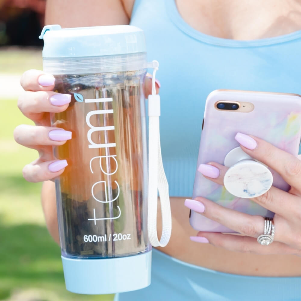 girl holding her teami tea tumbler in her hand while texting