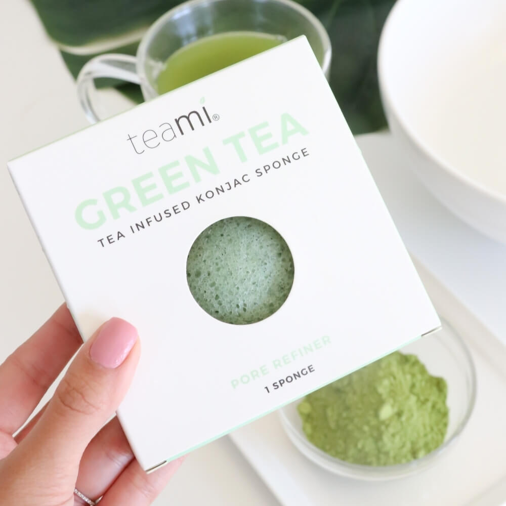 Hand with pink nails holding Teami tea infused konjac sponge in packaging box