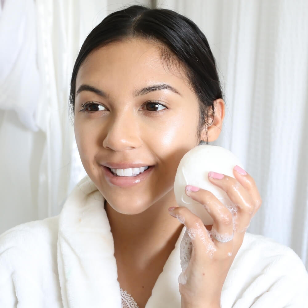 Woman holding Teami tea infused konjac sponge to her face