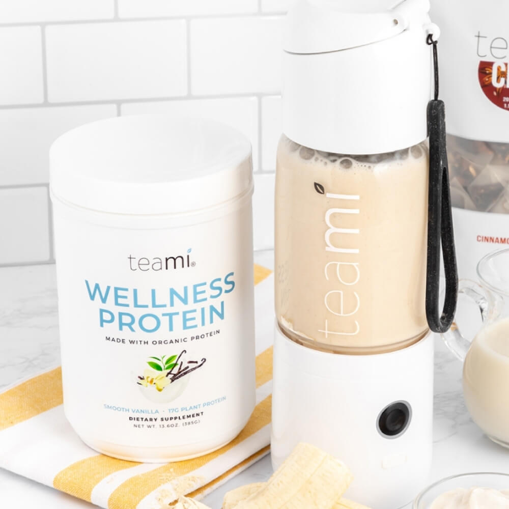 Teami MIXit portable blender in kitchen next to tub of Teami wellness protein