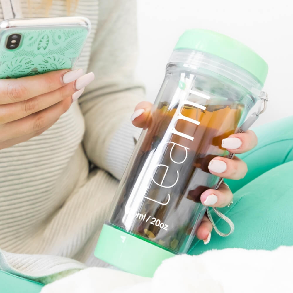 girl holding mint teami tea tumbler and phone