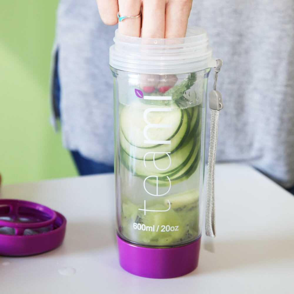 cucumber and fruit being placed into teami tea tumbler