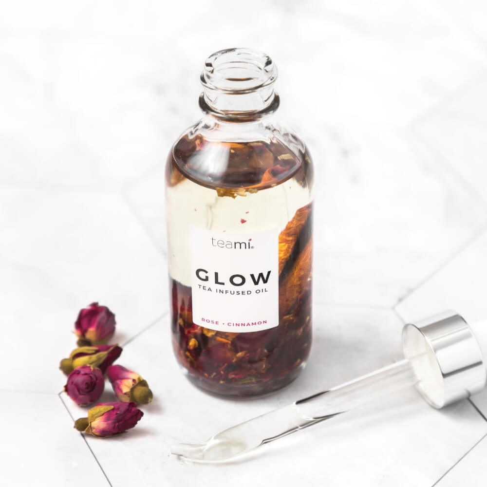 bottle of Teami glow oil with rose and cinnamon on marble surface