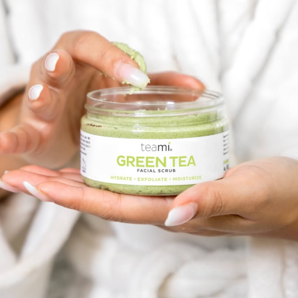 Person with pink nails holding pot of Teami green tea facial scrub 