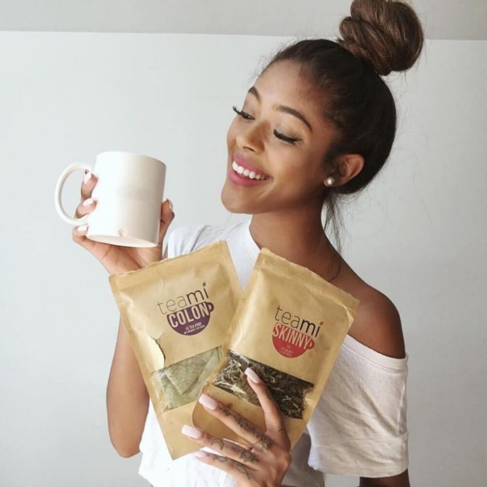a girl holding a cup of tea and teami colon and teami skinny tea in her hands