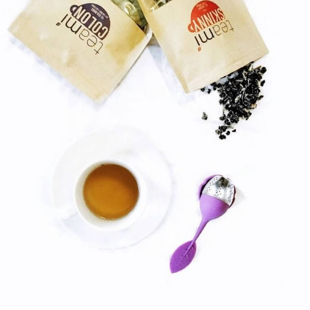 a cup of tea next to tea strainer, teami skinny and teami colon