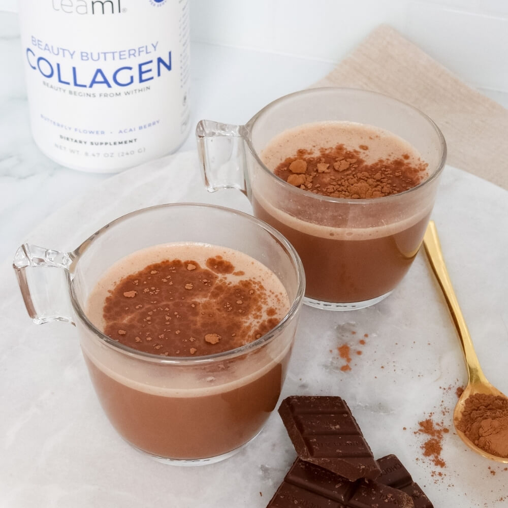 Glasses of chocolate drink with tub of Teami beauty butterfly collagen in background 