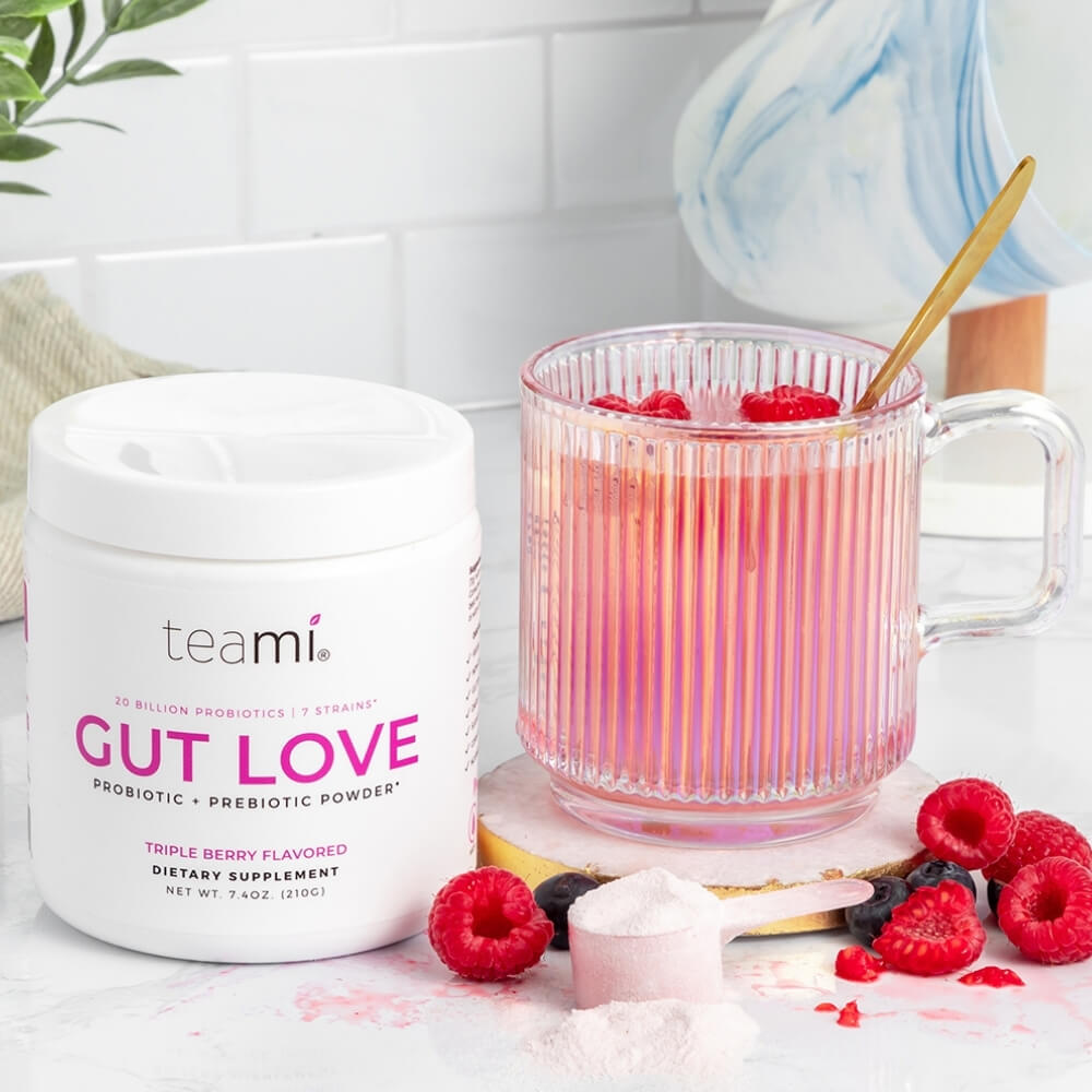 tub of Teami Gut Love triple berry flavour on kitchen counter with glass of drink