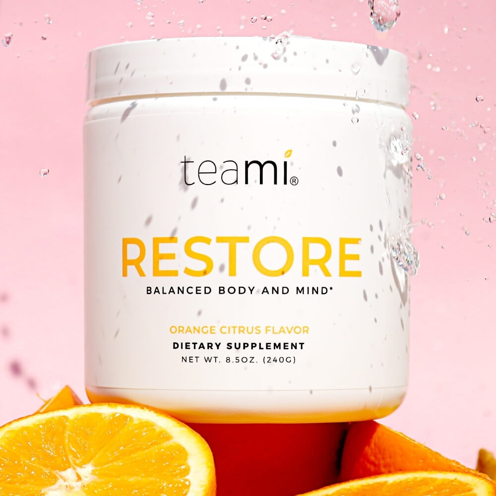 tub of Teami Restore supplement on pink background being sprinkled with water