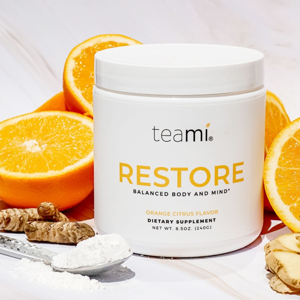 tub of Teami Restore supplement on counter with orange fruit
