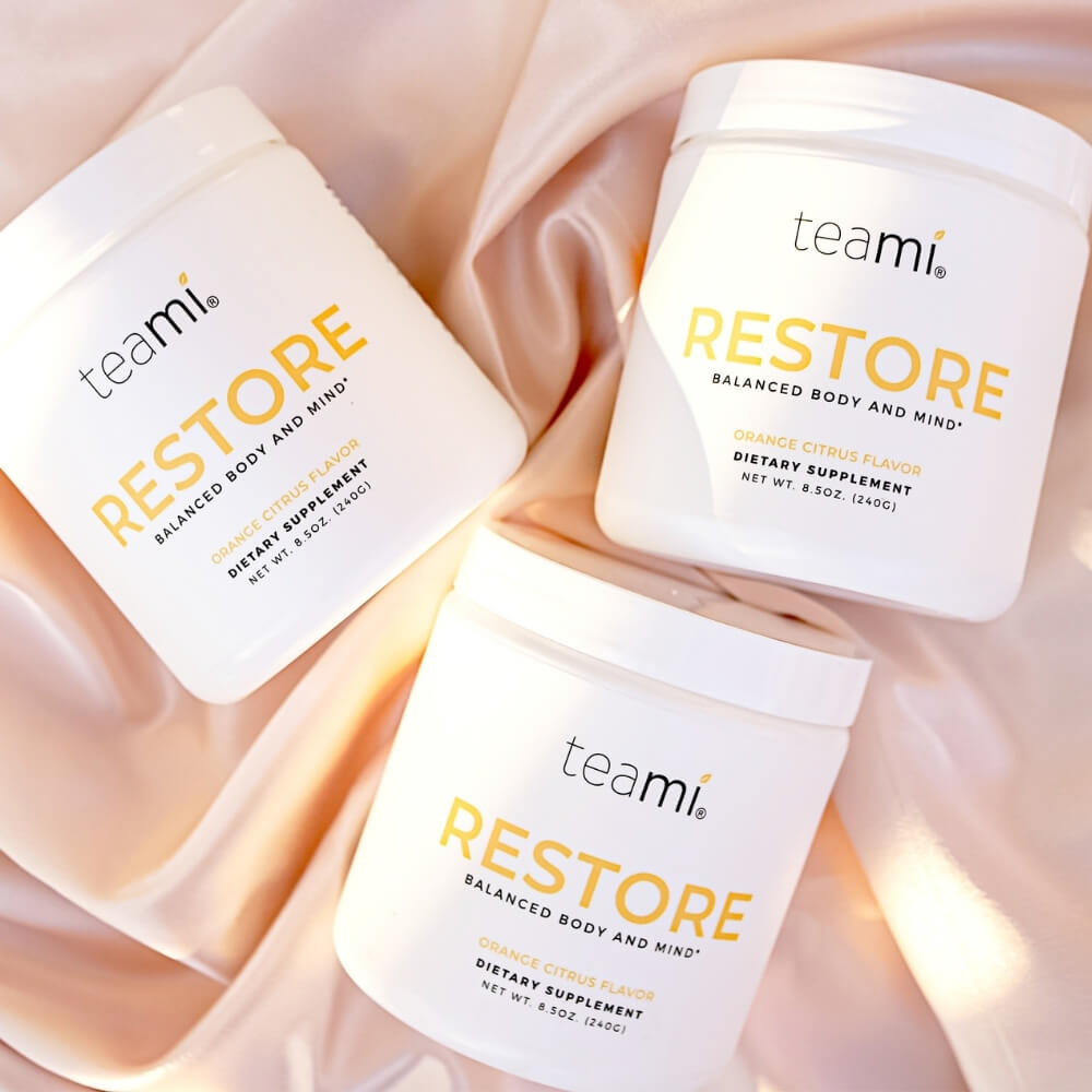three tubs of Teami Restore supplement on satin background