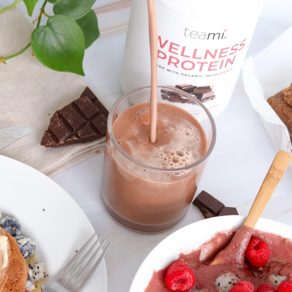 glass of drink containing teami wellness protein chocolate flavour