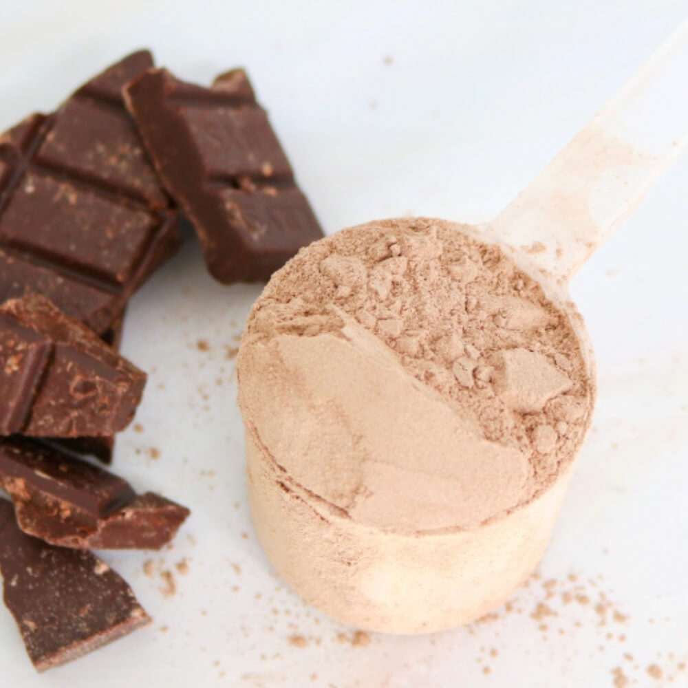 scoop of Teami rich chocolate flavoured wellness protein next to chocolate 
