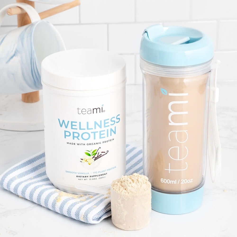 tub of teami wellness protein smooth vanilla flavour next to scoop and teami tea tumbler