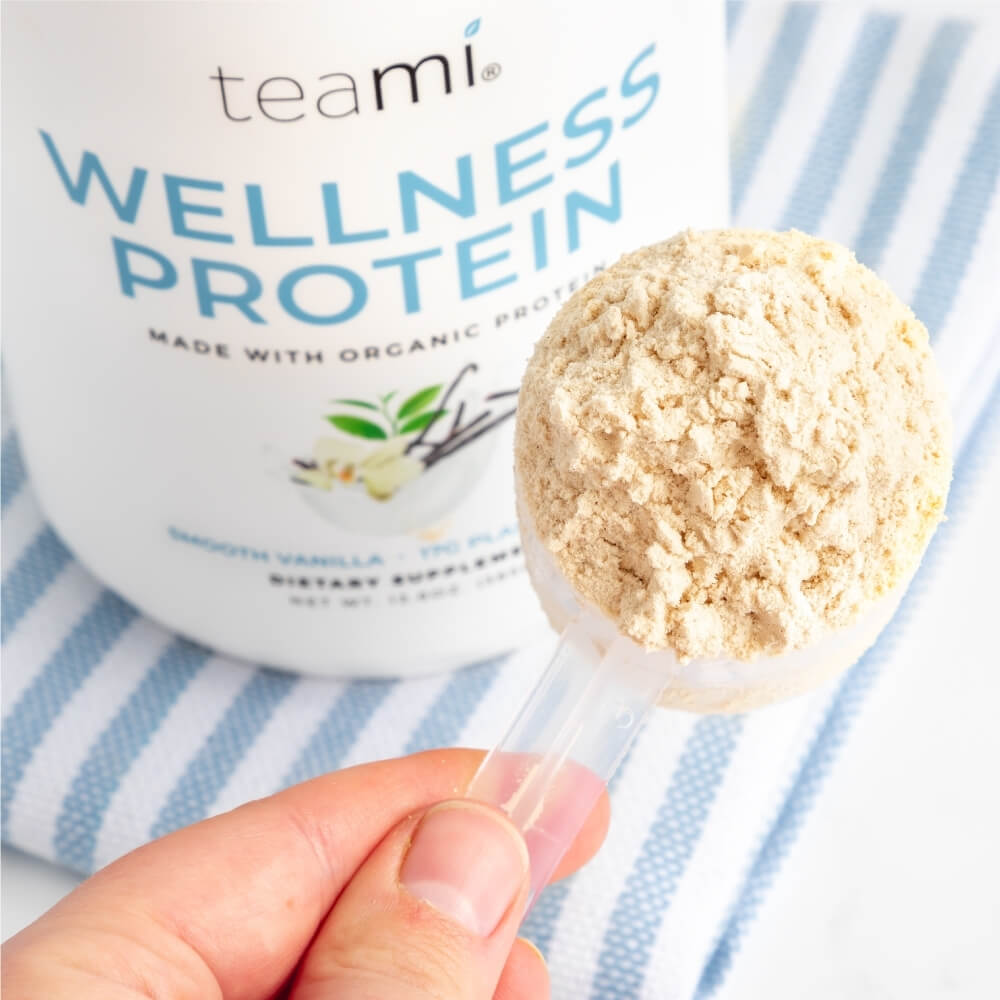 someone holding scoop of vanilla flavour teami wellness protein 